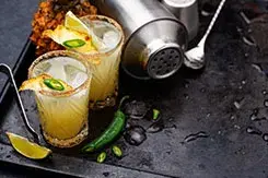 Cócteles refrescantes con piña y jalapeño junto a una coctelera, propuestas creativas de mixología moderna.